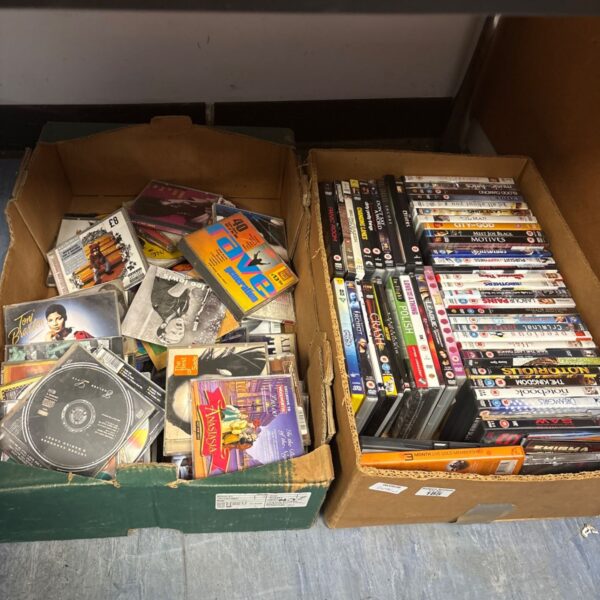 Mixed lot of music CDs and DVDs in a cardboard box.