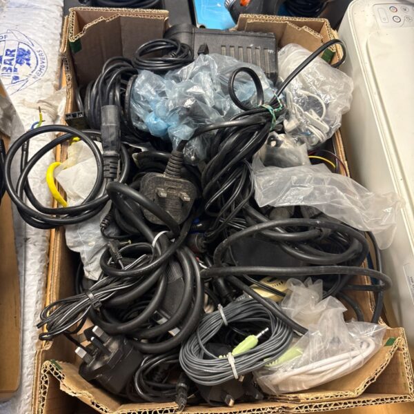 Mixed lot of cables, chargers, and headphones in a cardboard box.