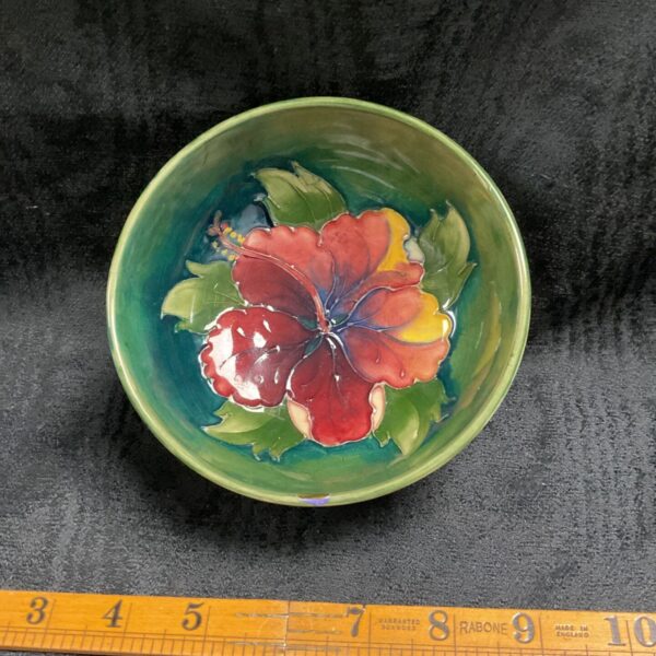 Vintage Moorcroft hibiscus bowl with floral design and green glaze.