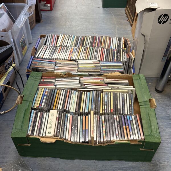 Large lot of mixed music CDs in a green container.