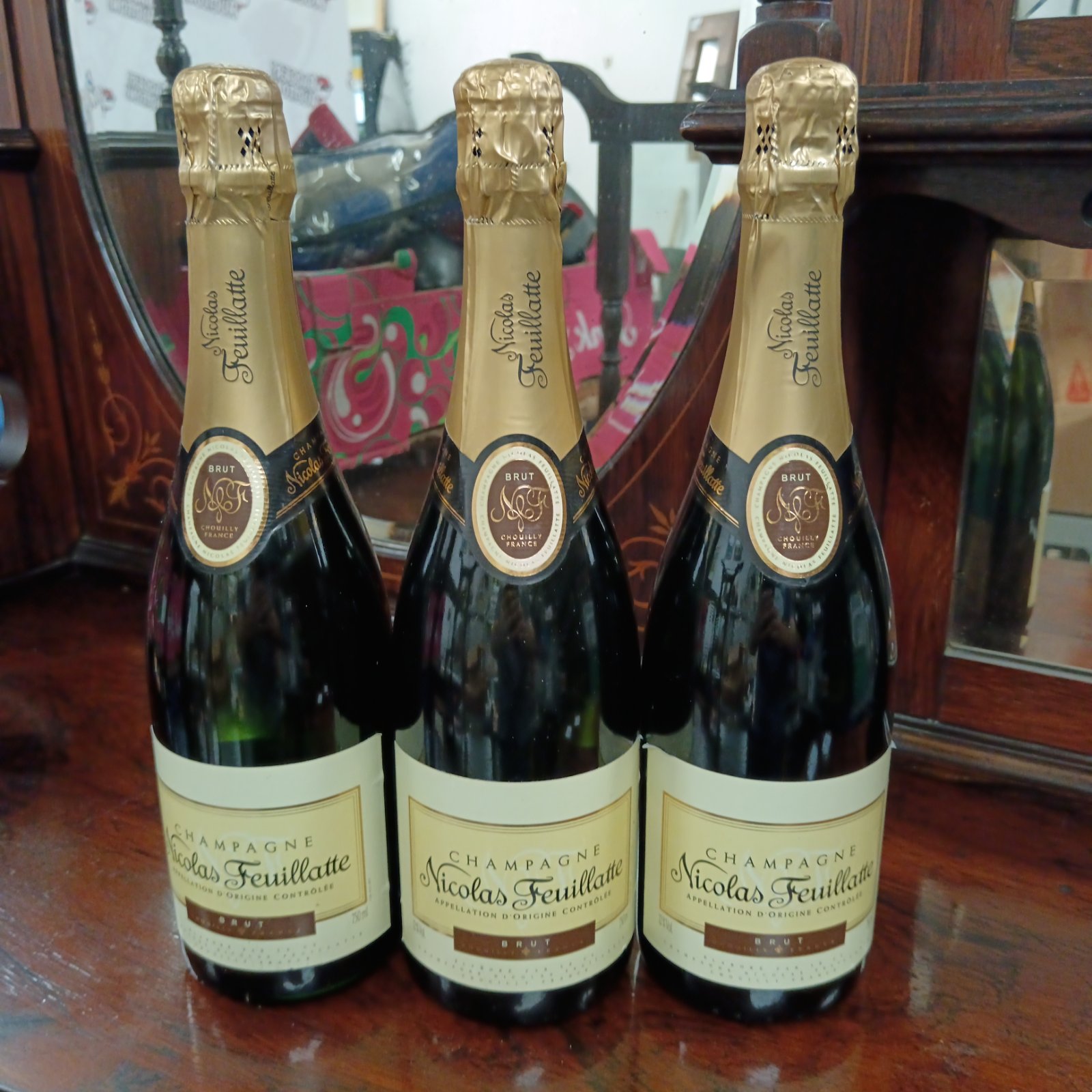 Three sealed bottles of Nicolas Feuillatte Champagne presented for auction.