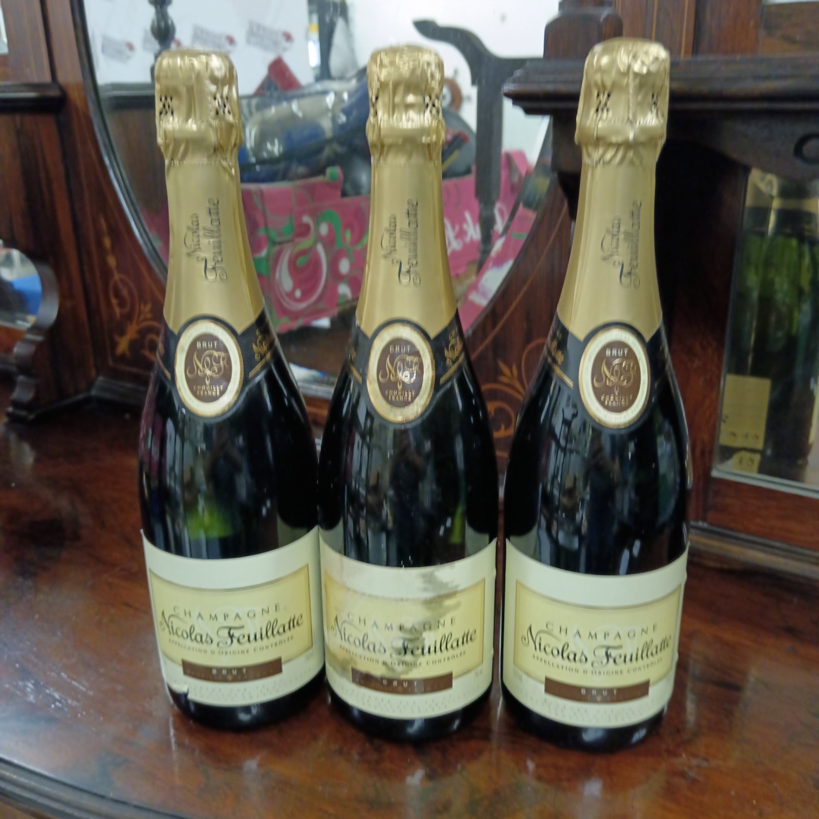 Three sealed bottles of Nicolas Feuillatte champagne presented on a table.