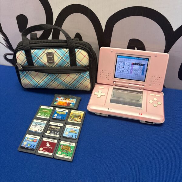 Pink Nintendo DS console with case and games, handheld gaming system.
