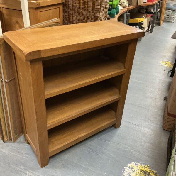 Vintage oak bookcase with three shelves for books and storage.