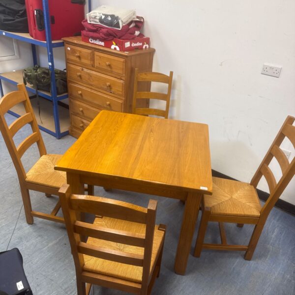 Light oak dining table and four chairs in a room setting.