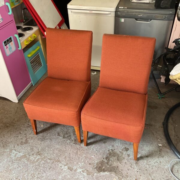 Pair of vintage orange fabric chairs with a retro style.