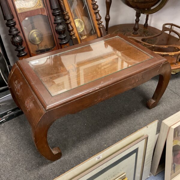 Intricately carved Oriental coffee table with glass top and ship carvings.