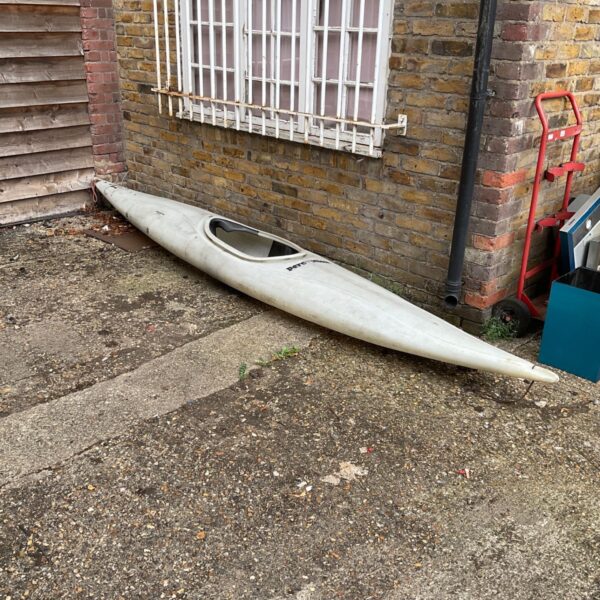 Blue Perception canoe resting against a brick wall.