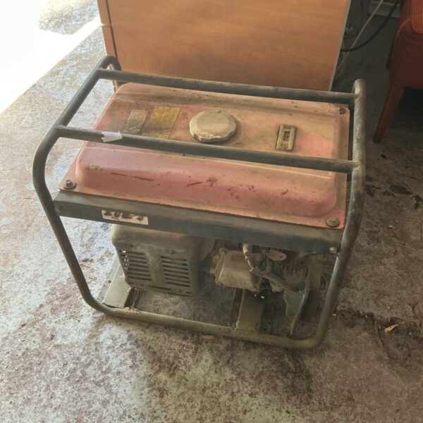 Vintage petrol generator with metal frame and handle.