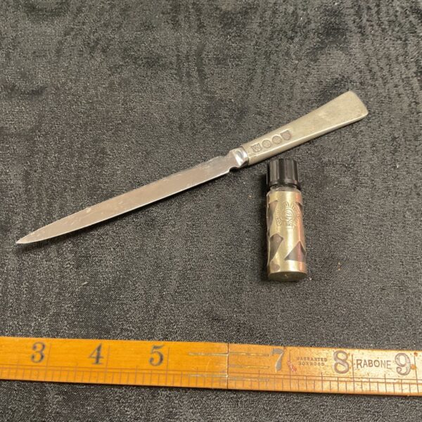 Antique pewter letter opener and perfume bottle set on a white surface.