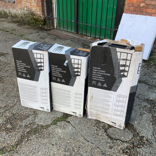 Three boxes of unopened plastic shelving units for storage.