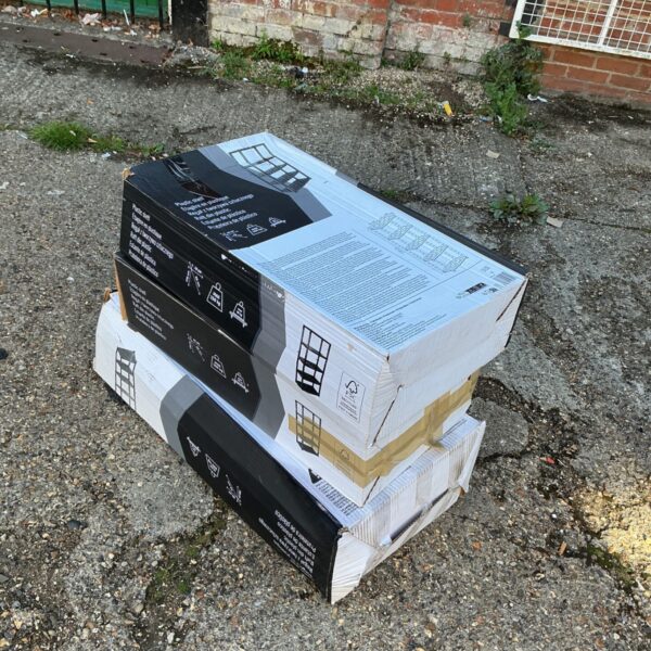 Three boxes of plastic shelving units stacked for storage.