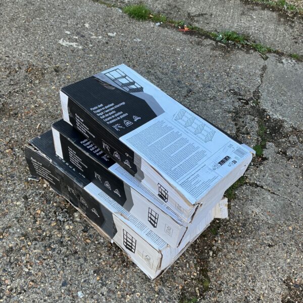 Three boxes of plastic shelving units stacked for storage.