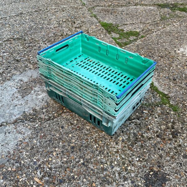Stack of four durable plastic storage crates for garden or workshop.