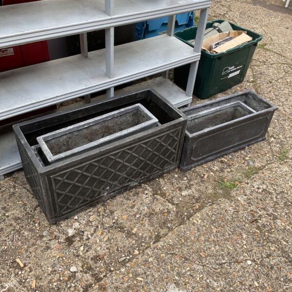 Rectangular plastic garden planters stacked for storage.