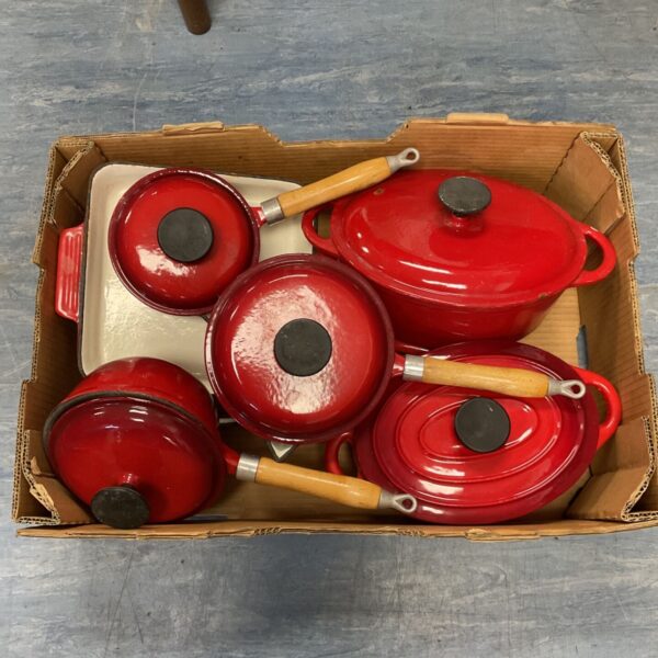 Vintage red cast iron enamel cookware set displayed in a cardboard box.