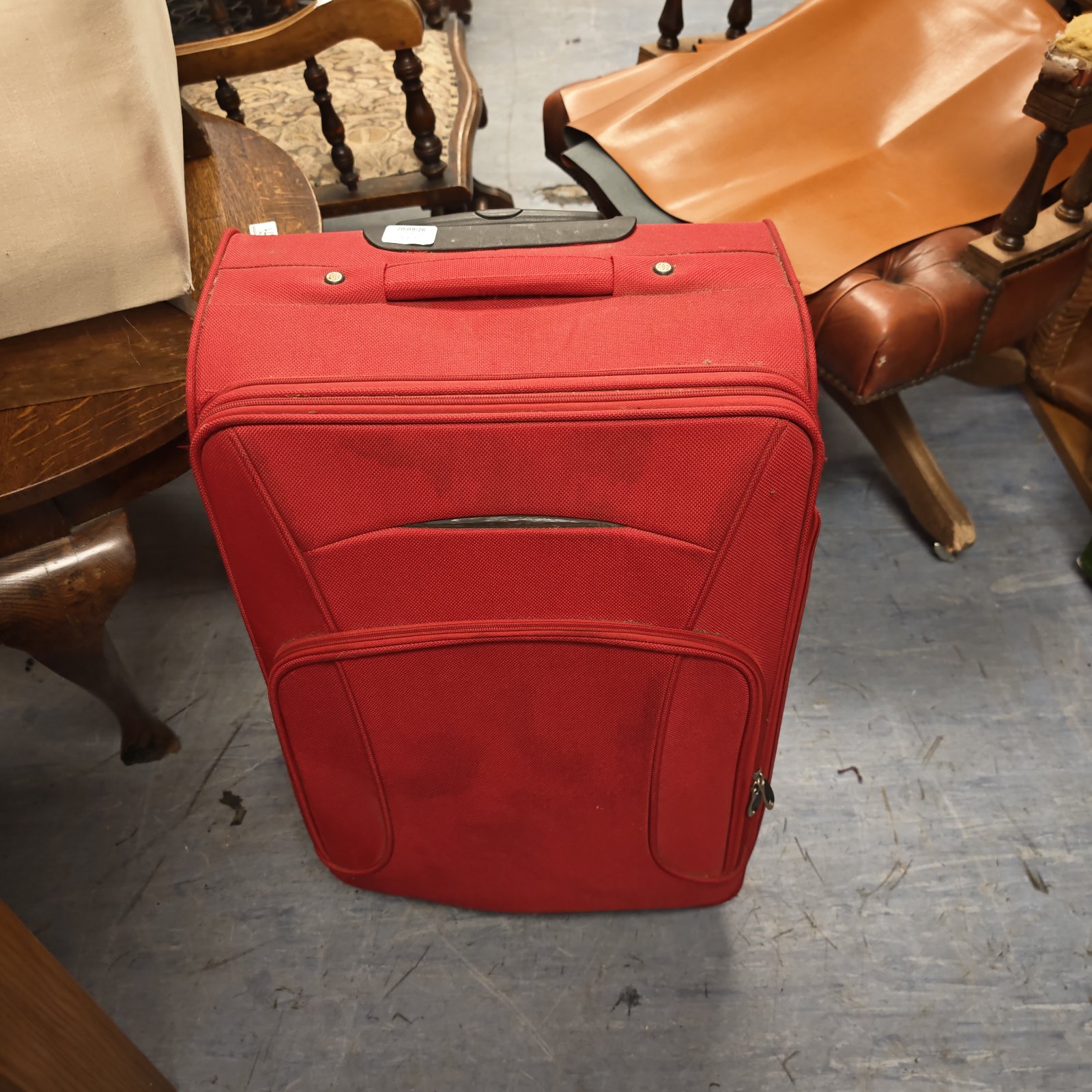 Red rolling suitcase with wheels and handle, ideal for travel.