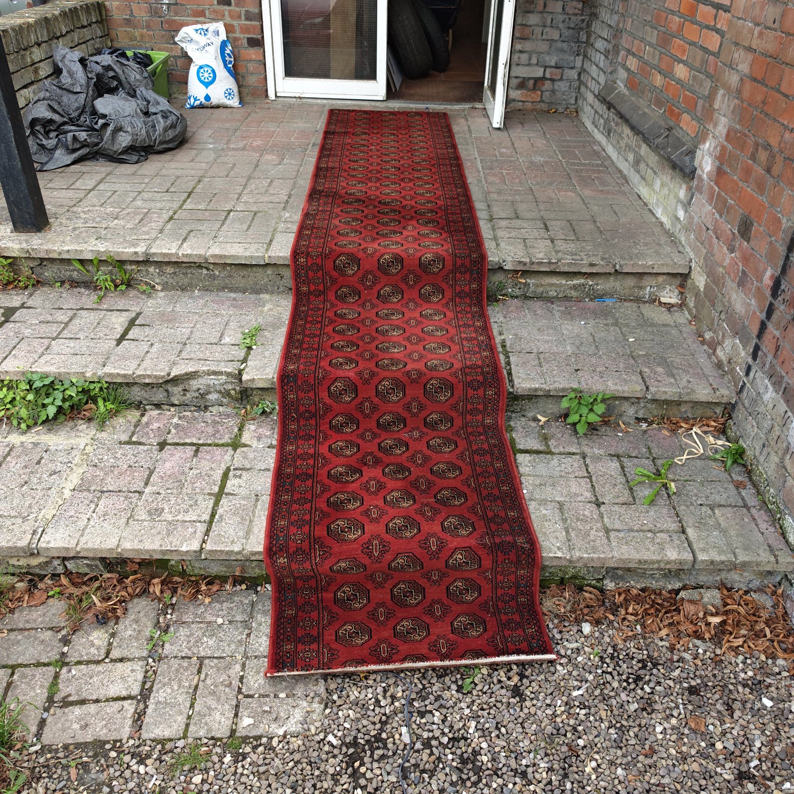 Red runner rug displayed in a hallway, showing oriental pattern.