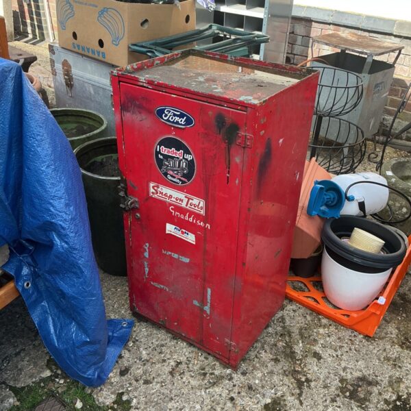 Vintage red Snap On tools cabinet with Ford logo and wear.