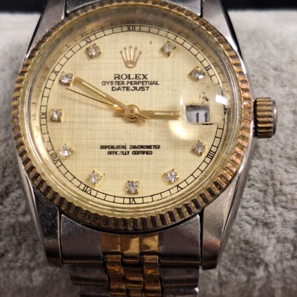 Replica Rolex gents watch with gold tone and date display.