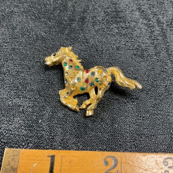 Vintage rhinestone horse brooch with red, green, and blue stones.