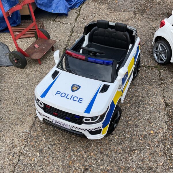 Red ride on police car for children's outdoor play.