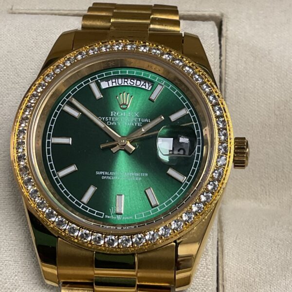 Gold tone Rolex Day Date reproduction watch with green dial.