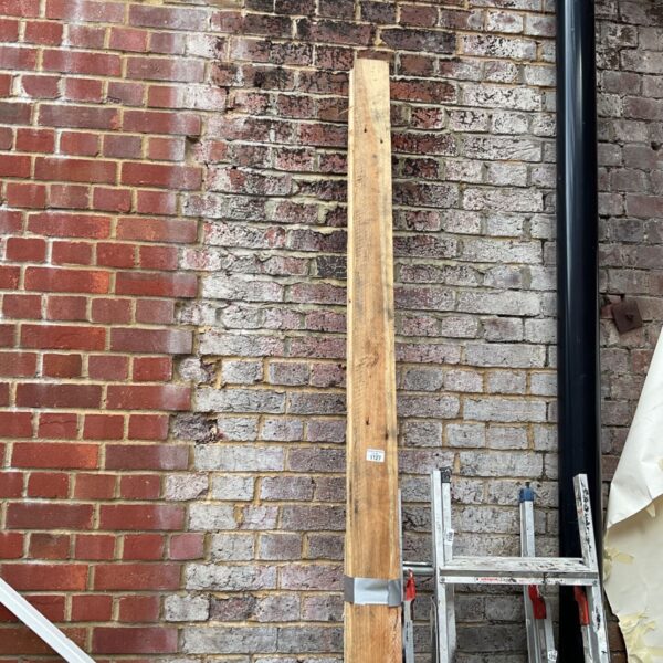 Bundle of rough sawn timber leaning against a brick wall.