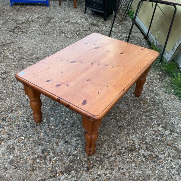 Rustic pine coffee table with turned legs in a home setting.