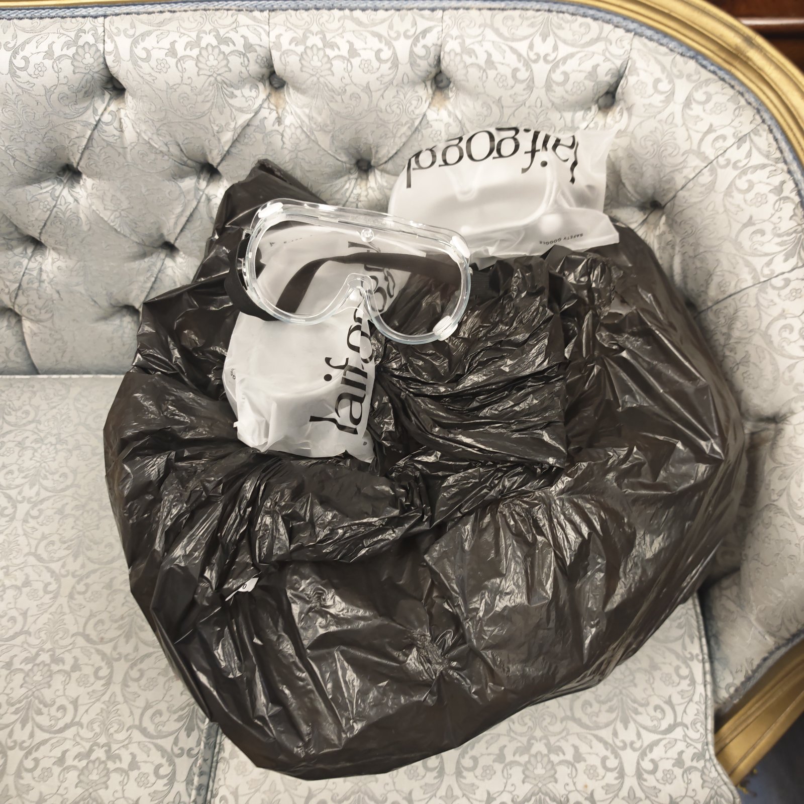 Bulk lot of clear safety goggles in a black bag.