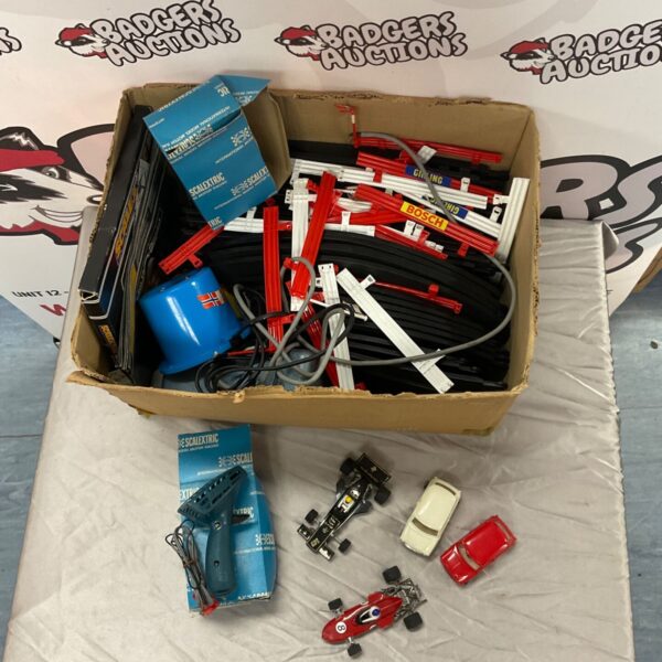Box of vintage Scalextric track, cars, and racing accessories.