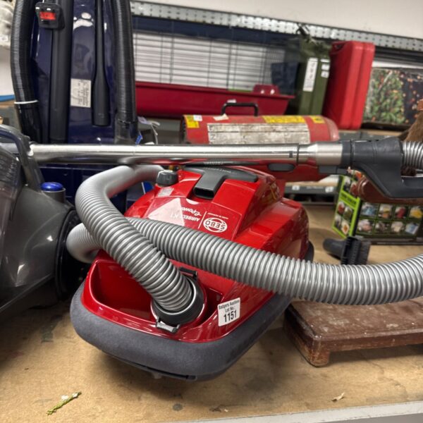 Red Sebo Airbelt K1 Stowaway cylinder vacuum cleaner with hose attached.