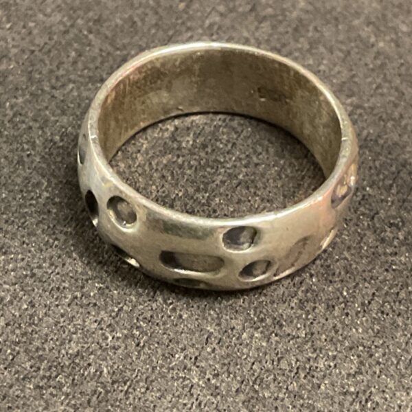 Polished silver band ring with circular cut-outs, size M.