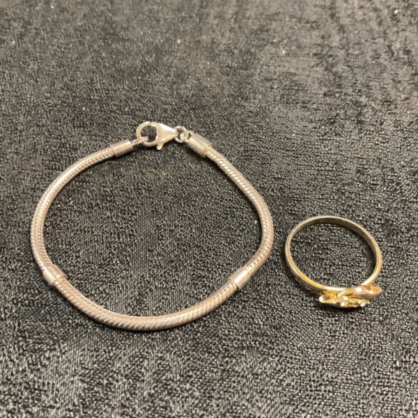 Silver bracelet and white metal ring set displayed on a dark surface.