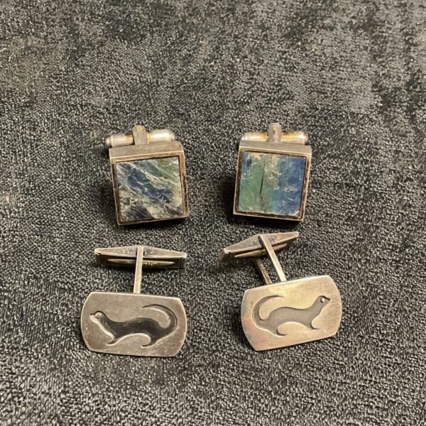 Silver cufflinks featuring an otter design and iridescent Spectrolite stone.