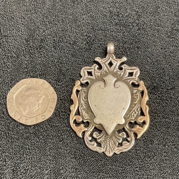 Antique silver and gold fob with a coin for scale.