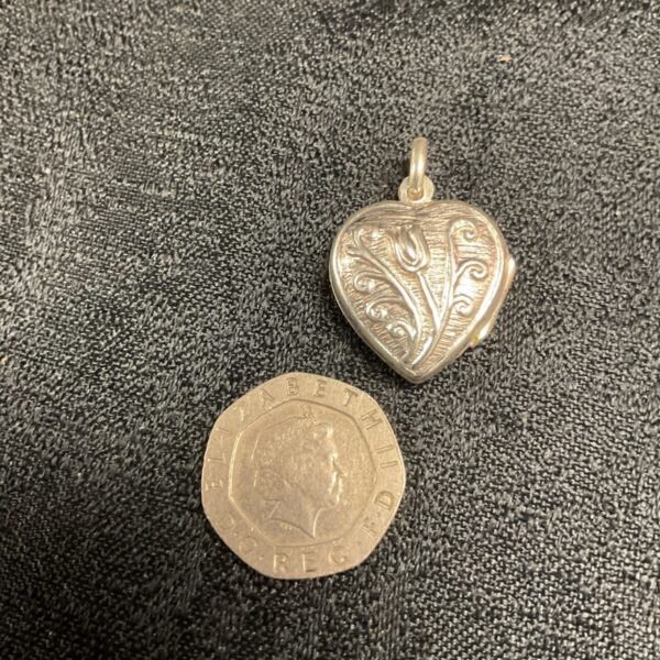Silver heart locket displayed with a coin for scale.