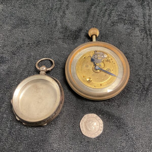 Open silver pocket watch case showing the movement.