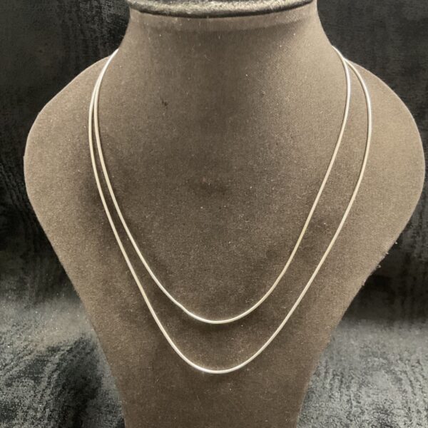 Silver snake chain necklaces layered on display.
