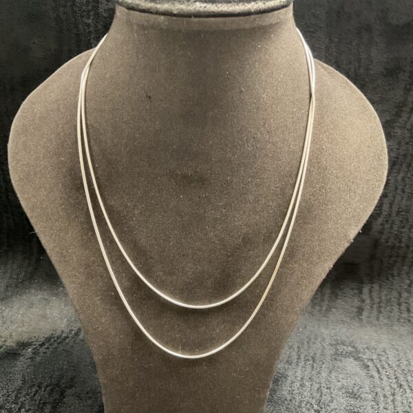 Silver snake chain necklaces displayed on a bust.