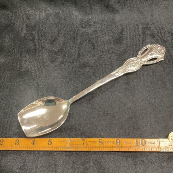 Antique silver serving spoon with ornate handle.