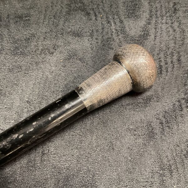 Antique silver topped walking cane with patterned handle.