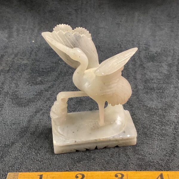 Detailed soapstone heron sculpture on a textured base.