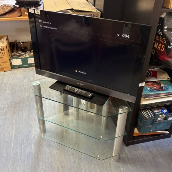 Sony Bravia LCD TV with remote and glass stand, side view.