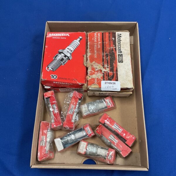 Mixed lot of Honda, Ford, and Champion spark plugs in original packaging.
