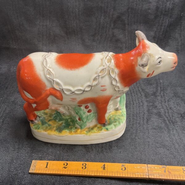 Vintage Staffordshire cow figurine with orange and white glaze.