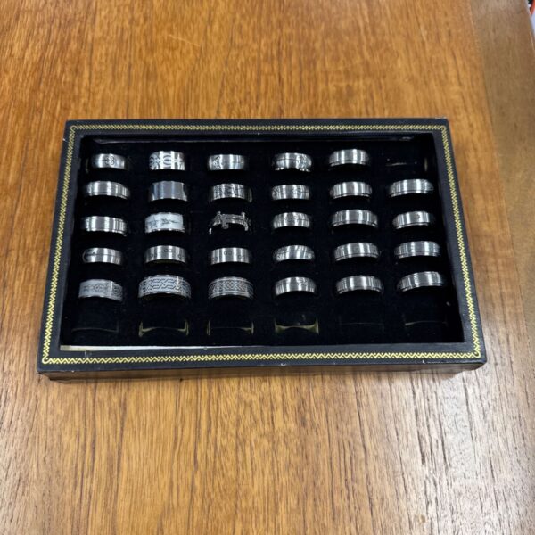 Assorted stainless steel gents rings in a display lot.
