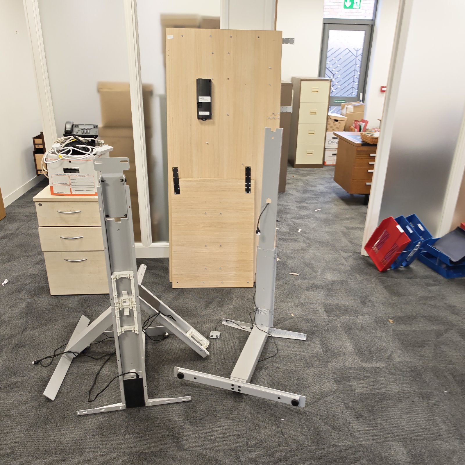 Adjustable height standing desk with wooden top and metal frame.