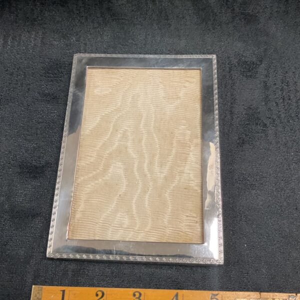 Antique sterling silver photo frame with embossed pattern.