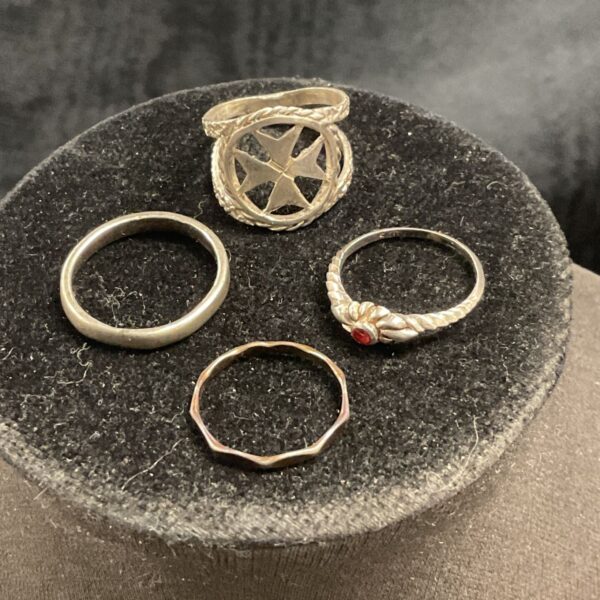 Mixed lot of four sterling silver rings on a display stand.
